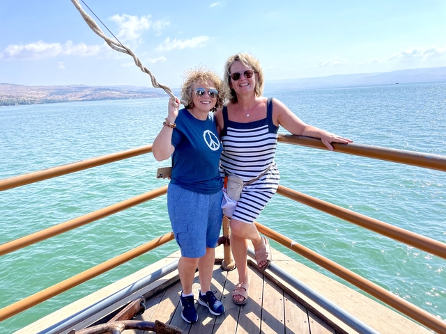       Two women on a boat with a lake in the background.
  