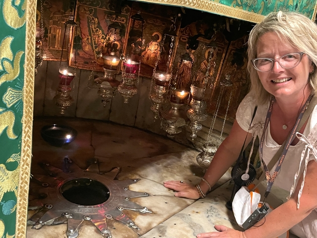       Woman next to an ornate interior altar with oil lamps.
  