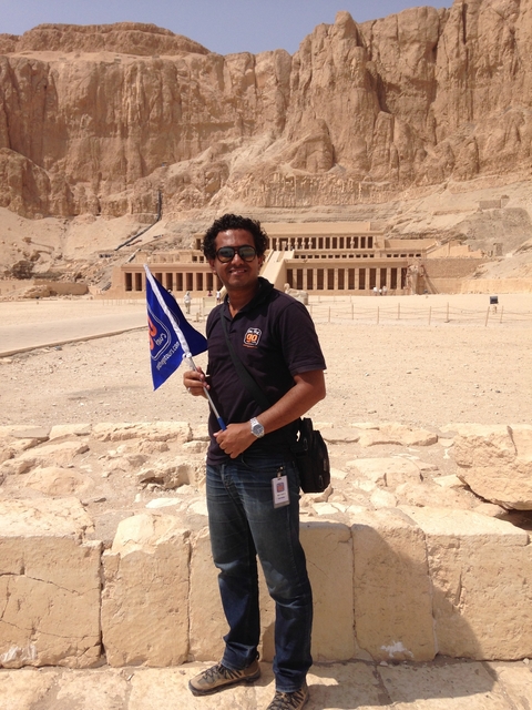       Person with a tour flag in front of an ancient Egyptian mortuary temple.
  