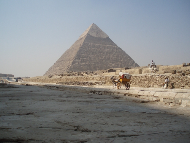       Pyramid with people and a horse-drawn cart.
  