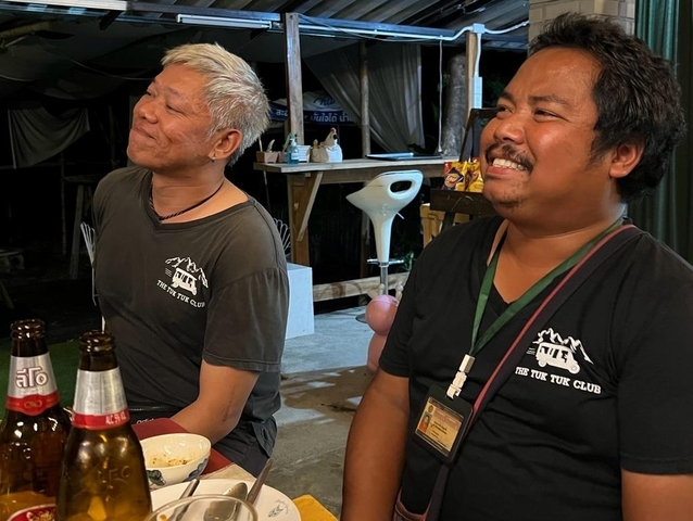 Two people sitting at a table with drinks, smiling.