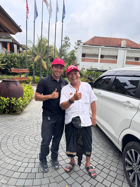 Two men posing cheerfully in front of a modern building.