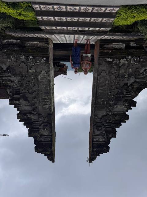 Two women standing between a traditional Balinese gate with beautiful architecture.
