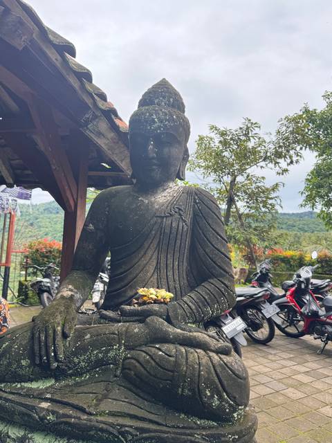 A large stone Buddha statue with offerings in front.