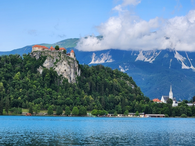 A scenic lake with mountains and cloudy sky in the background.