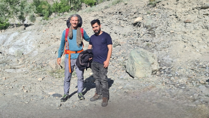 Two people standing and posing at a rocky landscape.
