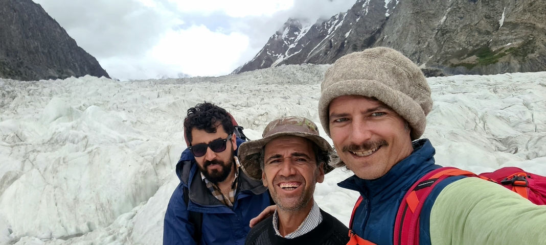 Three people smiling in front of a glacier.