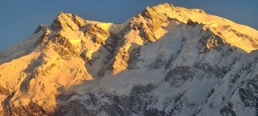 Golden light illuminating snowy peaks at sunset.
