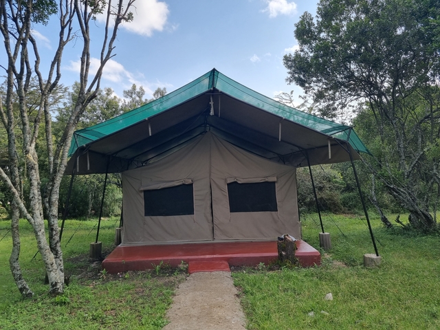 Exterior view of a safari tent setup in a natural setting.