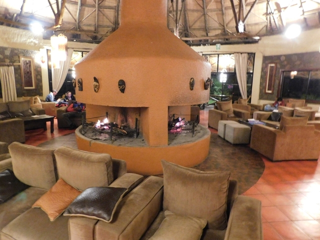       Cozy hotel lounge with central fireplace and seating.
  