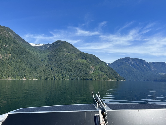 Scenic view of mountains and a lake with forested slopes and blue sky.