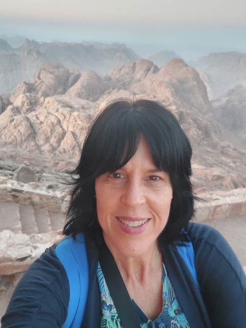       Close-up of a woman smiling in a rocky landscape.
  