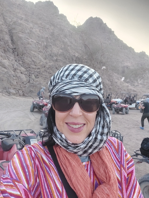 Woman in a headscarf posing with ATVs in the background.