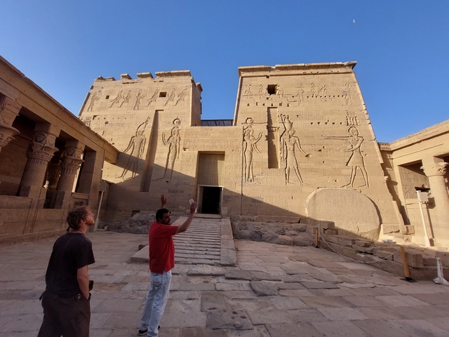       Two people exploring the ancient Philae Temple in Egypt.
  