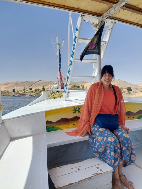Person sitting on a boat with a desert landscape in the background.