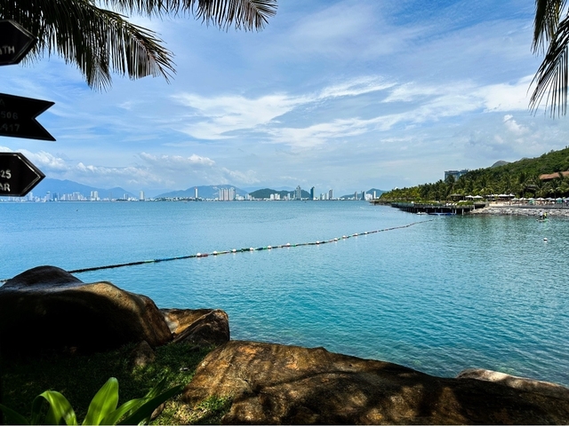       Coastal cityscape with buildings in the distance and clear blue water.
  