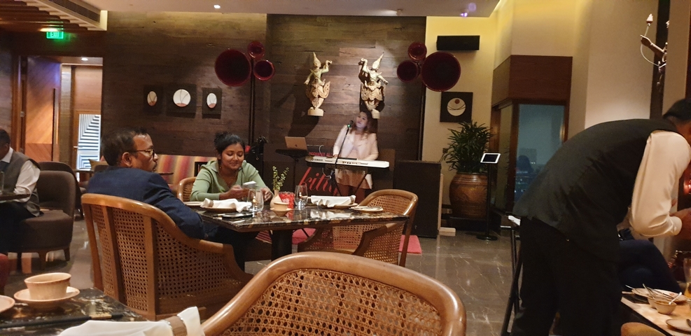       Indoor restaurant with diners and a live musician playing a keyboard.
  