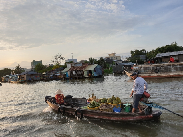 Man in a boat on a river with houses along the shore.