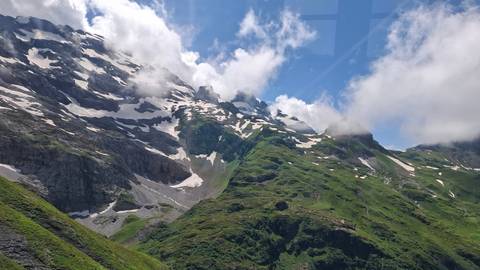 Mountain view with snow patches and a blue sky background.