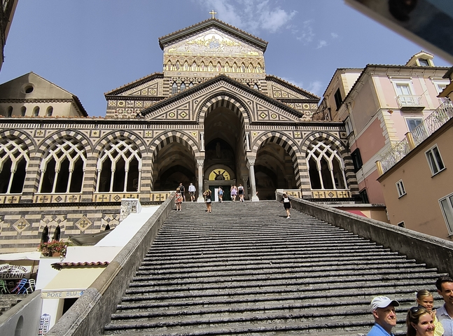 Ornate church facade with steps and people.