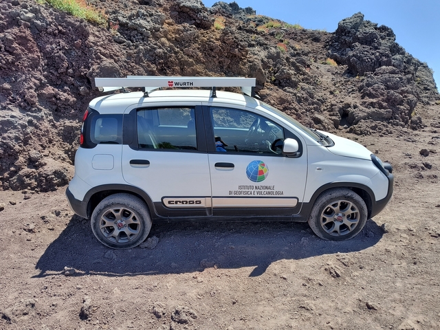       Car parked on a road with mountains in the background.
  