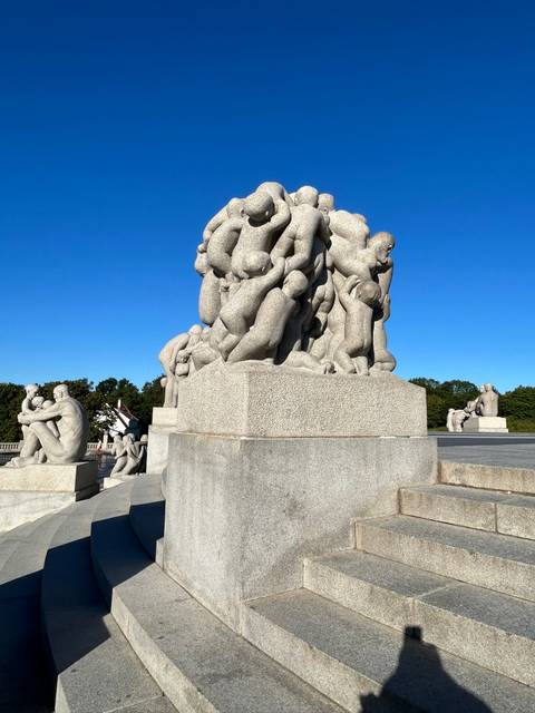       Stone sculpture of intertwined figures beside steps.
  