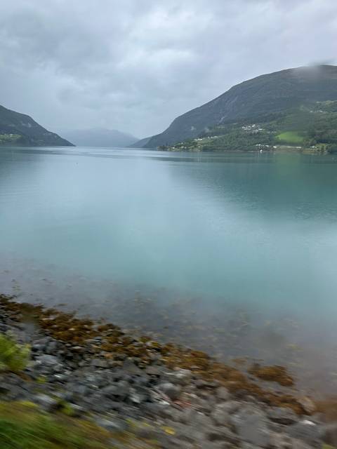       Rocky shoreline with calm waters in a fjord.
  