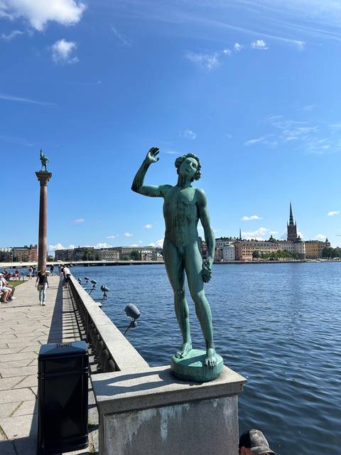       Statue on a bridge with cityscape in the background.
  