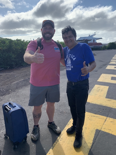       Two men smiling and giving thumbs up, standing outdoors.
  