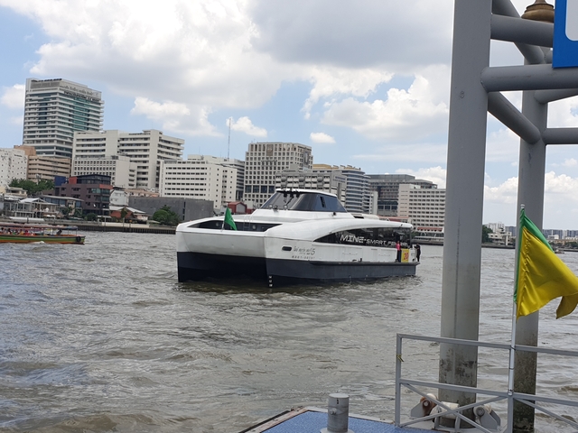 Boat cruising on a river with city buildings in the background.