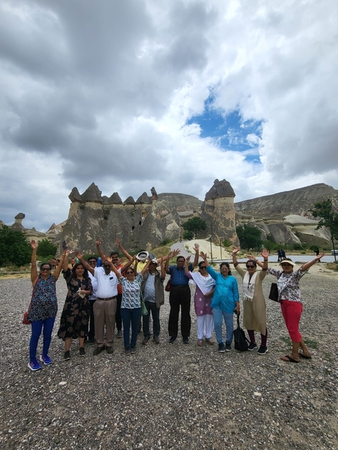 Tourists posing in front of unusual rock formations in a valley.