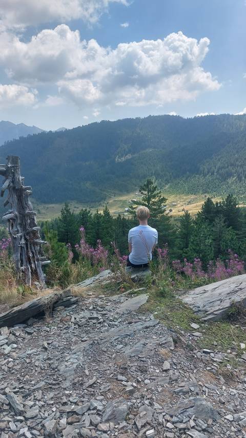 Person sitting on rocks overlooking a valley.