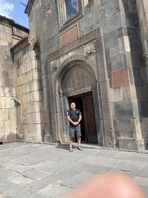       A person standing in front of a church entrance with ornate carvings.
  