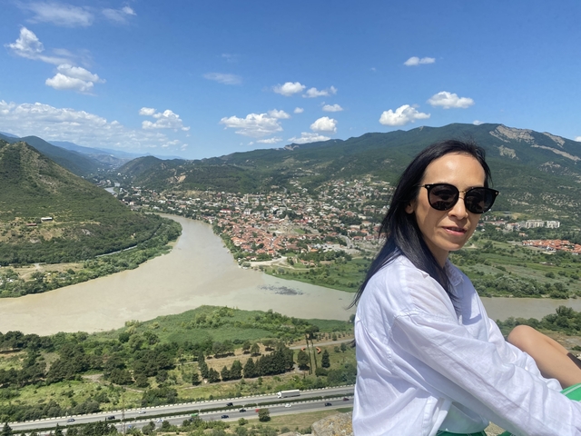       Woman with a view of a river and hills.
  