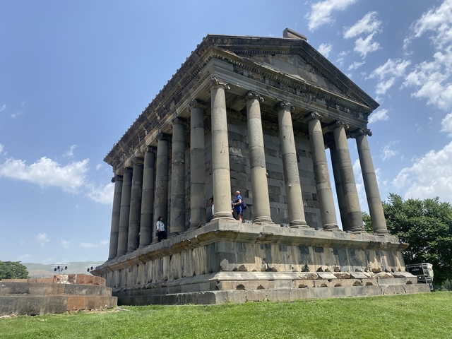       Ancient columned building with people around.
  