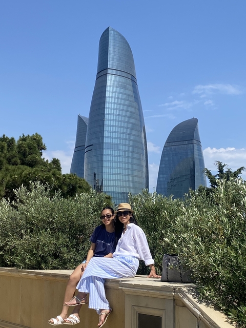       Two women posing with modern skyscraper in the background.
  