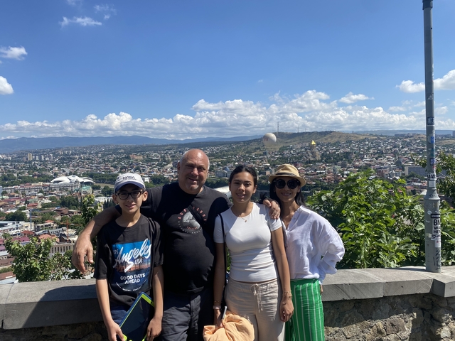       Family posing with a cityscape viewpoint.
  