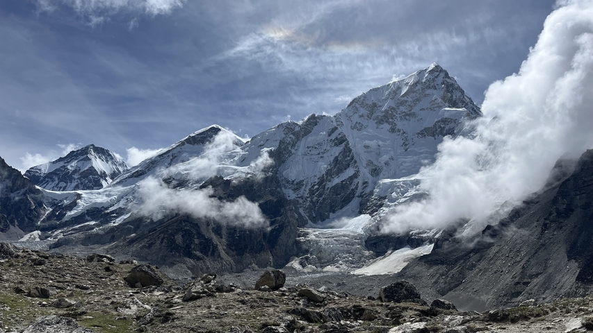 A dramatic view of mountains with snow and clouds.