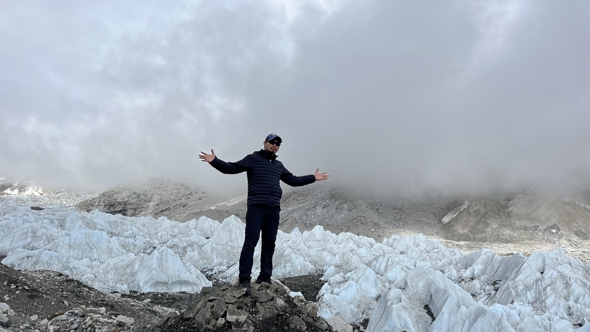 A person posing on a rocky terrain with ice formations.