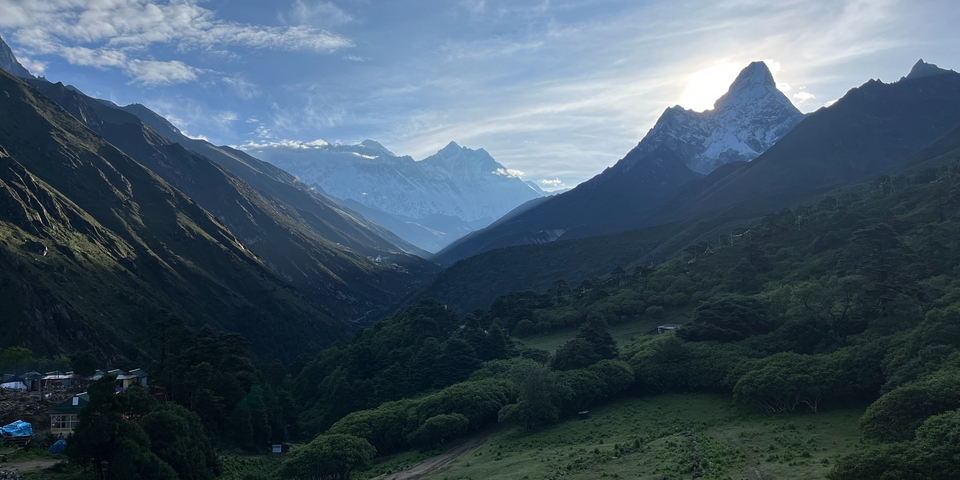 Mountain landscape with green valleys and snowy peaks.