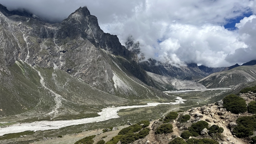Wide view of a mountainous landscape with a glacial river and rocky terrain.
