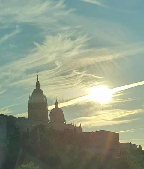 Silhouetted domes and spires of a cathedral at sunset with dramatic clouds.