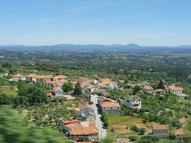       Aerial view of a town with red rooftops amidst green fields.
  