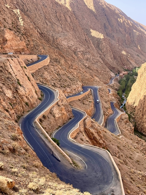 Winding mountain road with steep cliffs and sparse vegetation.