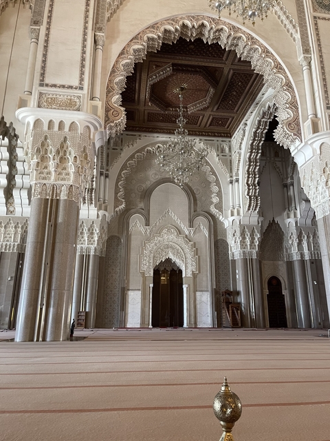 Intricate interior of a mosque with arches and chandeliers.