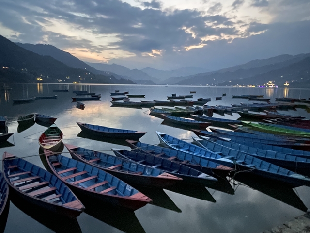 A lake with colorful boats during twilight.