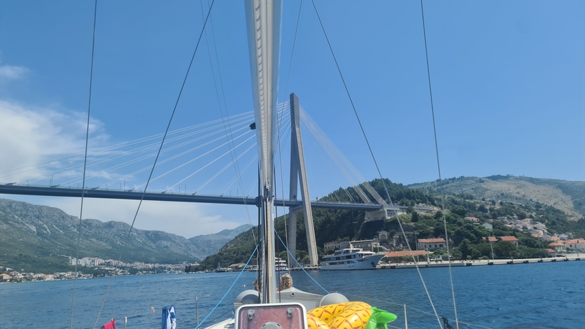 A bridge seen from a sailing boat with a mountainous background.