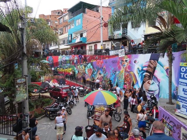       Colorful urban scene with graffiti walls and a bustling crowd.
  