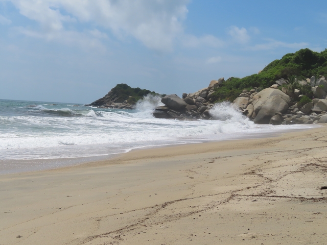       Waves crashing on a rocky beach with clear skies.
  
