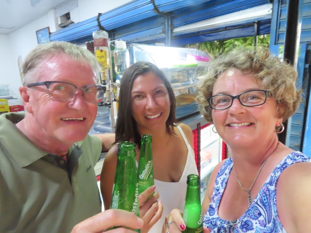       Three people with drinks, smiling in a restaurant setting.
  
